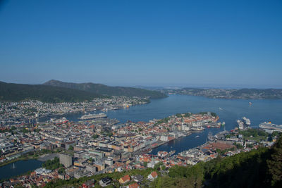 High angle view of townscape by sea against clear blue sky