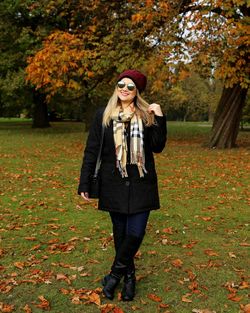 Portrait of young woman wearing sunglasses standing at park during autumn