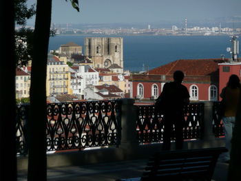 People in city by sea against sky