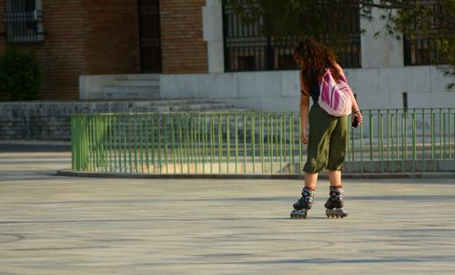 Rear view of woman rollerblading against building