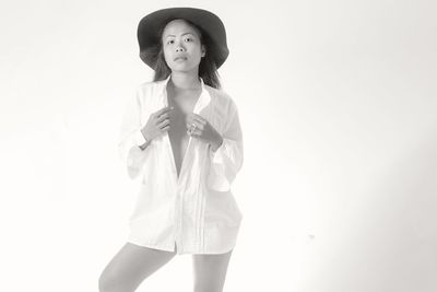 Portrait of young woman standing against white background