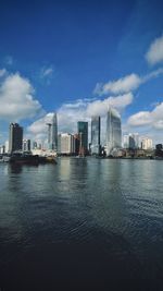 Buildings by river against sky