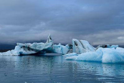 Tranquil scene with icebergs against cloudy sky