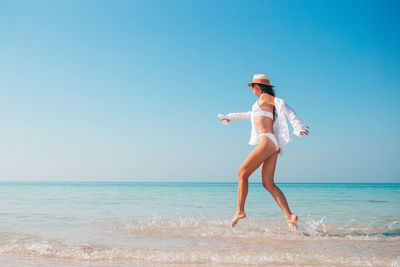 Full length of woman walking on beach against sky