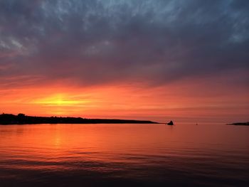 Scenic view of sea against cloudy sky at sunset