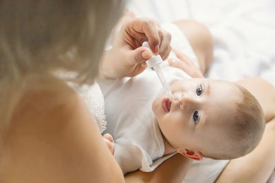 Mother feeding medicine to baby through pipette at home