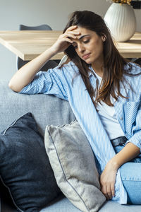 Young woman sitting on sofa at home