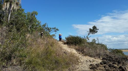 Rear view of people walking on landscape against sky