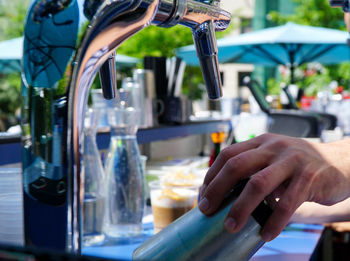 Cropped image of hand holding glass under machine at stall