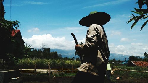 Side view of farmer standing on field against sky