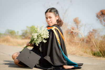 Happy girl sitting on tree against plants