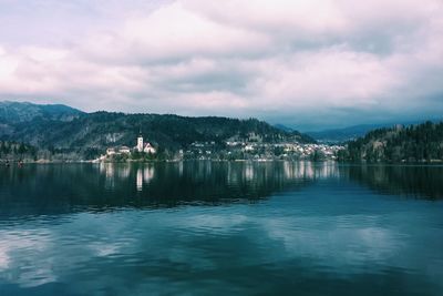 Scenic view of lake and town against cloudy sky