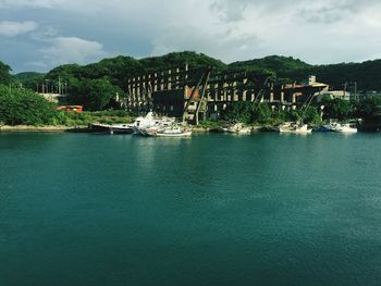 Boats in river against cloudy sky
