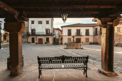 Empty bench by buildings in city