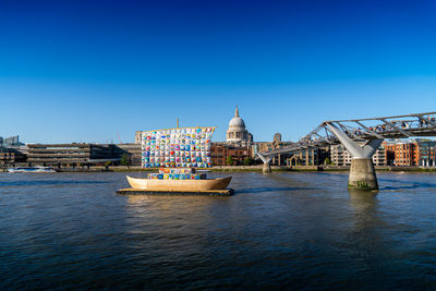 Bridge over river thames against buildings and barges in london city