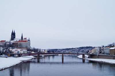 Bridge over river in city against clear sky