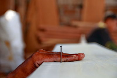 Cropped hand of carpenter by nail on wood