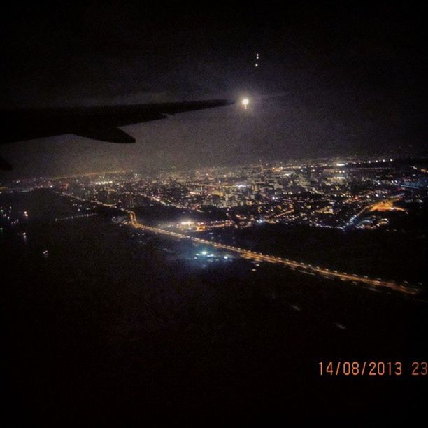 night, illuminated, cityscape, city, aerial view, architecture, building exterior, built structure, airplane, high angle view, crowded, transportation, air vehicle, flying, sky, moon, city life, copy space, dark, clear sky