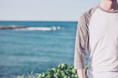 Midsection of man standing on beach against sea
