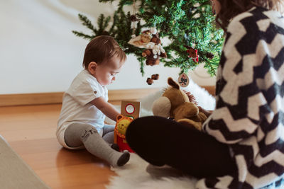 Mother and son spending leisure time by christmas tree at home