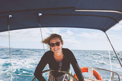 Happy woman with sunglasses on boat in sea