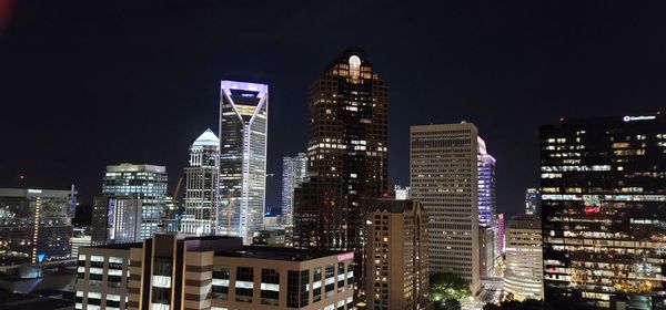 Illuminated buildings in city against sky at night