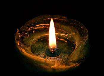 Close-up of lit candle against black background