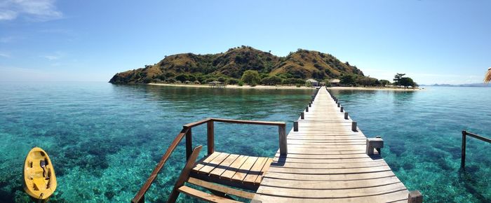 Pier over sea against clear blue sky