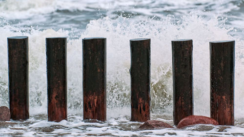 High wooden breakwaters in blue splashing sea waves, close up view. stormy day at sea.