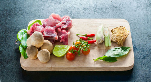 Tomatoes and meat on cutting board over table