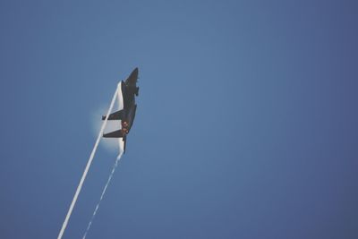 Low angle view of airplane flying against clear blue sky