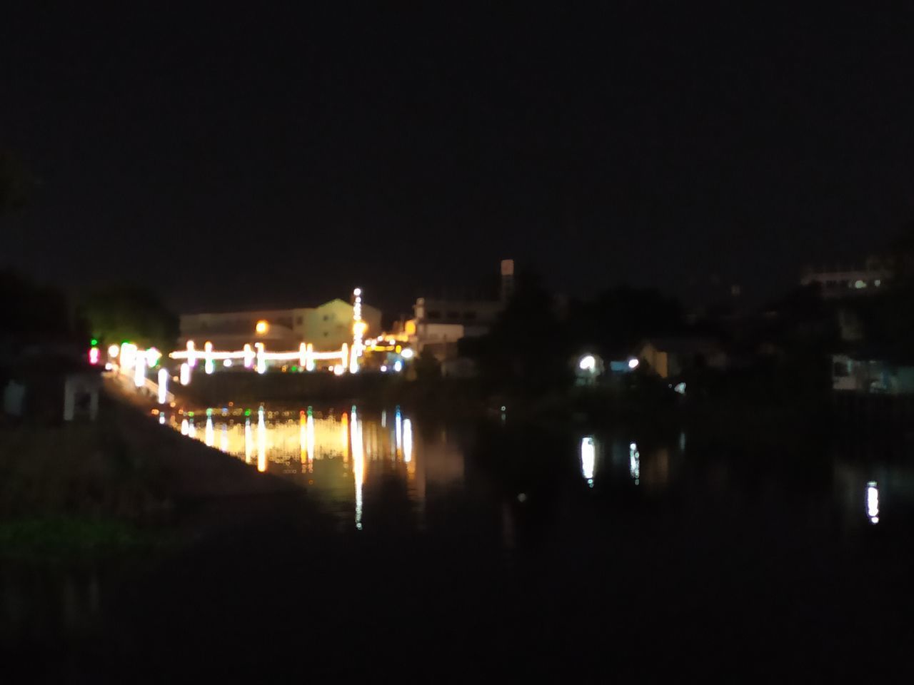 REFLECTION OF BUILDINGS IN WATER AT NIGHT