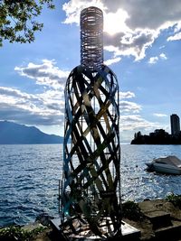 Metal structure in sea against sky