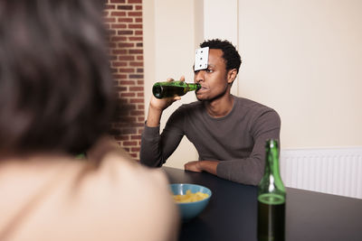 Midsection of woman holding bottle while standing against wall