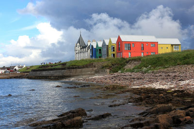 Buildings by river against sky