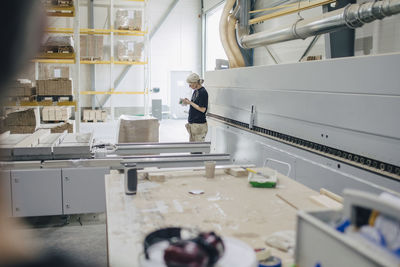 Worker standing by machinery at industry