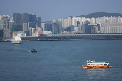 Boat sailing on sea against buildings in city