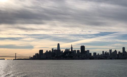 Sea with buildings in background at sunset