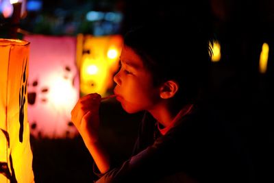 Side view of boy with illuminated lighting equipment at night