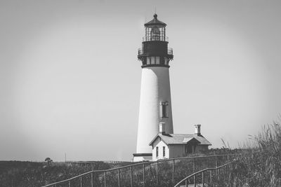 Low angle view of lighthouse by building against clear sky