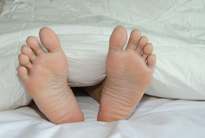 Low section of person relaxing on bed