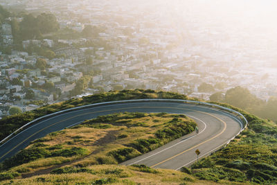 Aerial view of winding road against cityscape during sunset