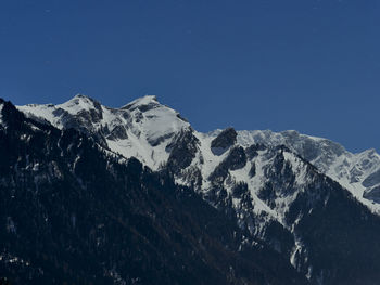 Scenic view of snowcapped mountains against clear blue sky