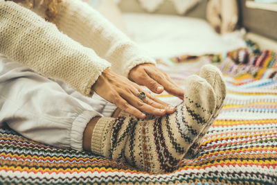 Low section of woman relaxing on bed