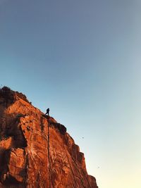 Low angle view of person on rock against sky