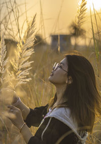 Young woman looking at plants during sunset