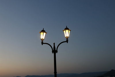 Low angle view of illuminated street light against sky