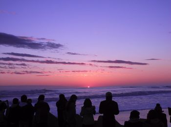 Silhouette people on beach against sky during sunset