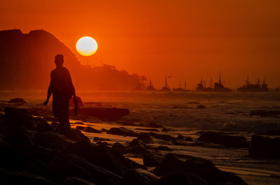 Silhouette man on beach against sky during sunset