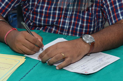 Cropped image of man holding paper on table